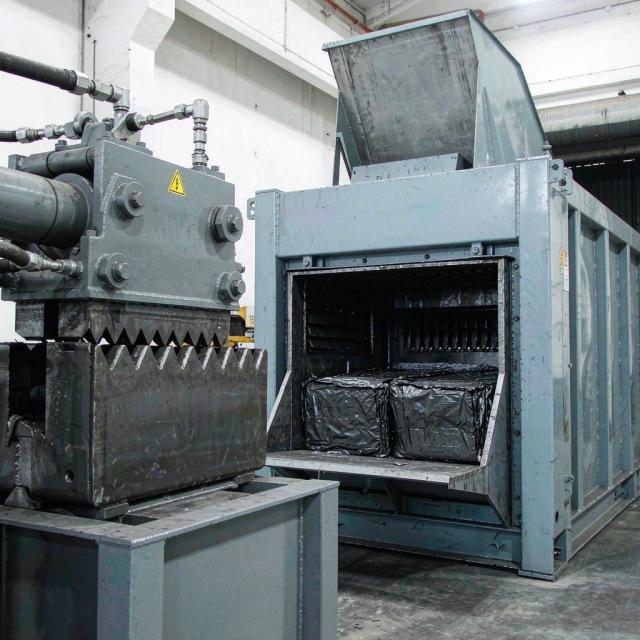 Hydraulic shearing and baling machinery producing dense scrap metal bales at a recycling plant