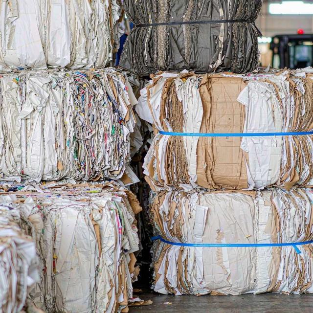Rolls of recycled containerboard produced from recovered waste paper in a paper mill